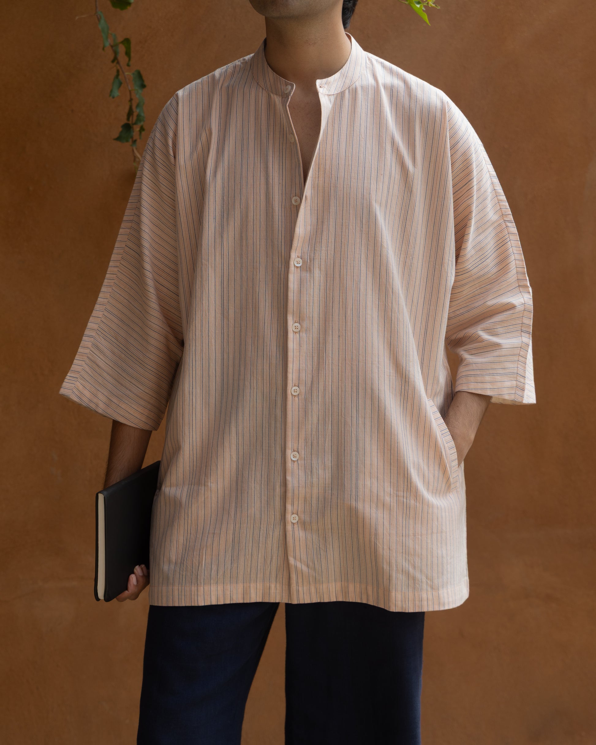 Eco-friendly men’s kimono-style shirt in earthy pink tones, featuring multi-stripe design and made from organic handspun khadi cotton.